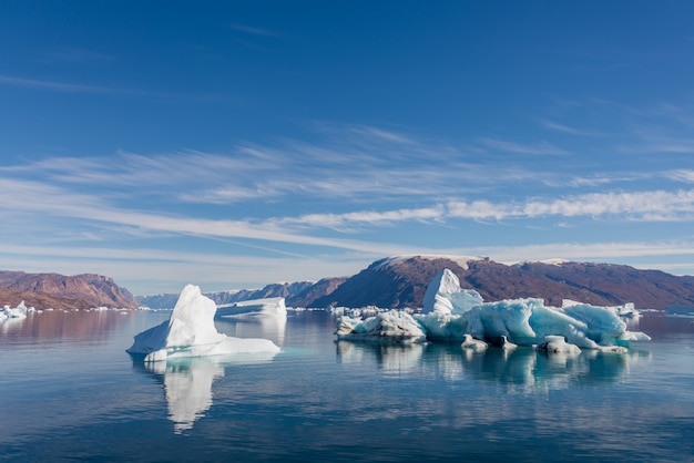 写真 穏やかな水の反射とグリーンランドフィヨルドの氷山。日当たりの良い天気。ゴールデンアワー。