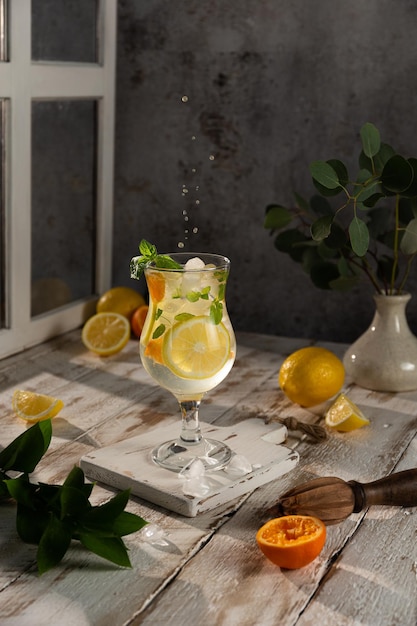 Icecold nonalcoholic lemon cocktail decorated with a sprig of mint on a light wooden background