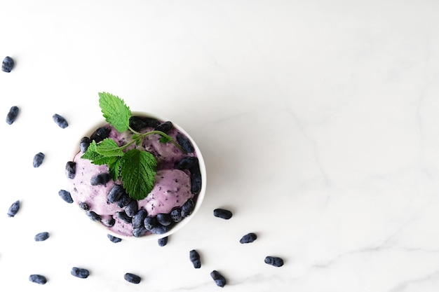 Icecream decorated with fresh berries of a honeysuckle and green leaves on white background