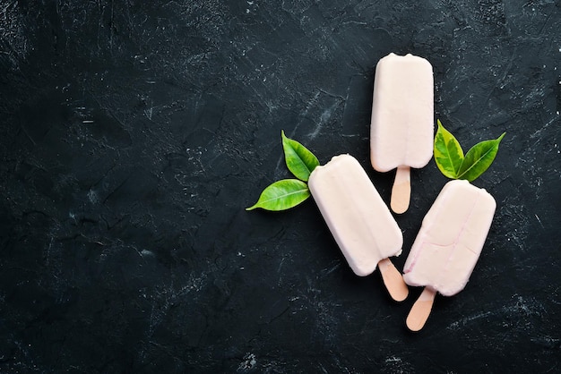 Icecream on a stick with white chocolate On a black background Top view Free copy space