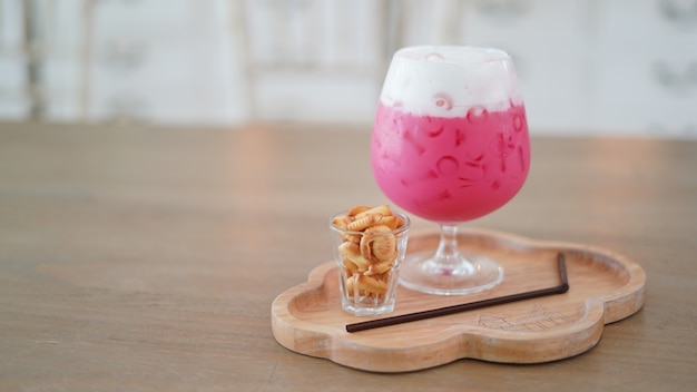 Iced aardbeimelk in het glas dient met kleine koekjes op de houten tafel