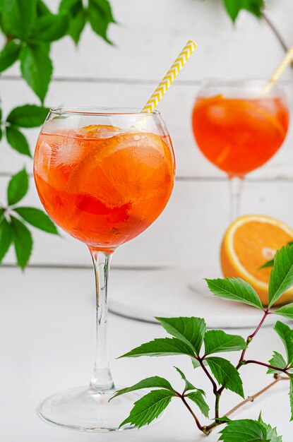 Iced aperol spritz cocktail with orange on white wooden background. Summer alcohol drink concept