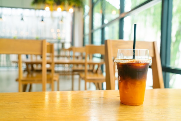 iced black coffee with orange yuzu juice cup on table in coffee shop cafe