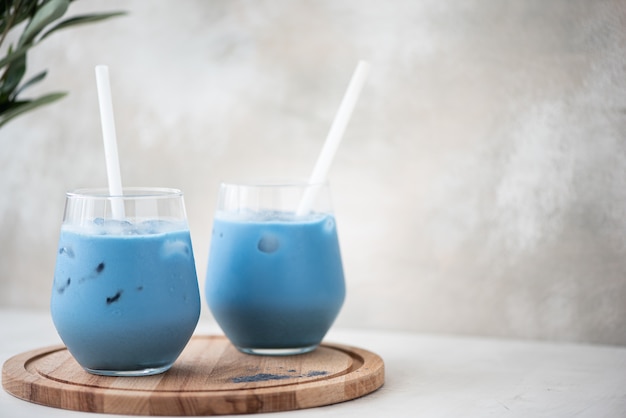 Iced blue matcha tea in glasses on a wooden board