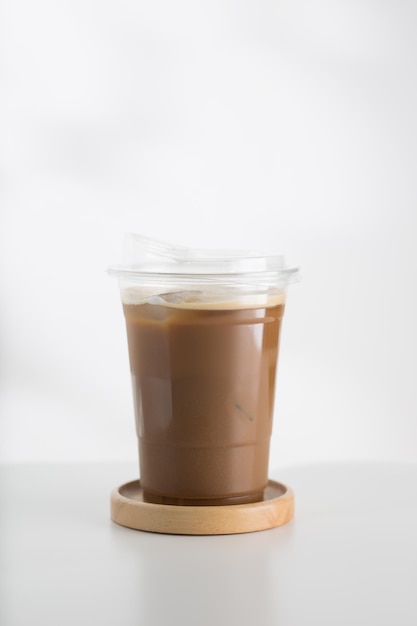 Photo iced cappuccino in a plastic glass on a white wooden table minimaliststyle picture