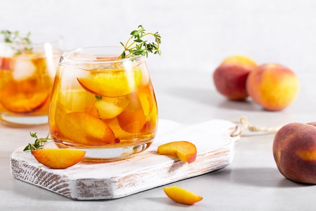 Photo iced carbonated tea with peaches and  thyme  in a glass