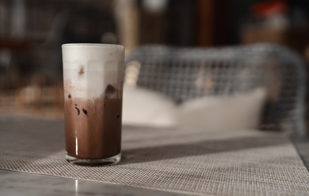 Iced chocolate or cocoa latte in glass on table with morning light, refreshing cold drink