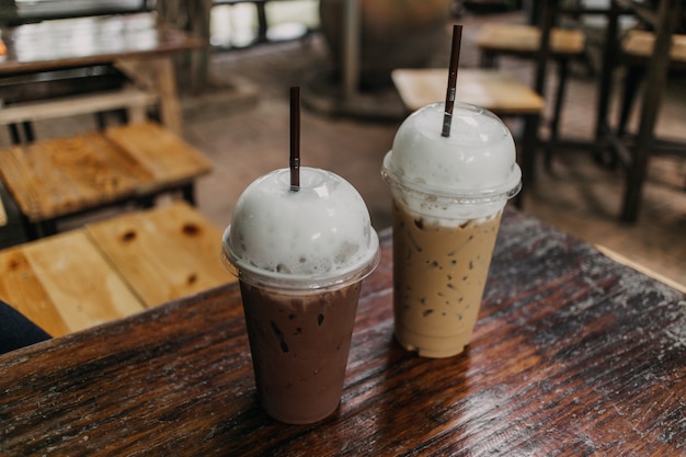 Foto il cacao e il caffè ghiacciati in plastica sono serviti sulla tavola di legno.