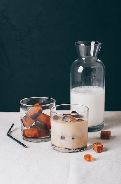 Iced coffe and milk on a white table with dark background.