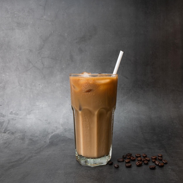 Iced coffee on cup with roasted coffee beans on a black\
background studio photo