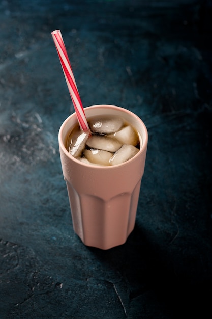 Iced coffee in a glass on a dark blue stone surface. Concept cooling drink, thirst, summer, cola with ice. flat lay, top view