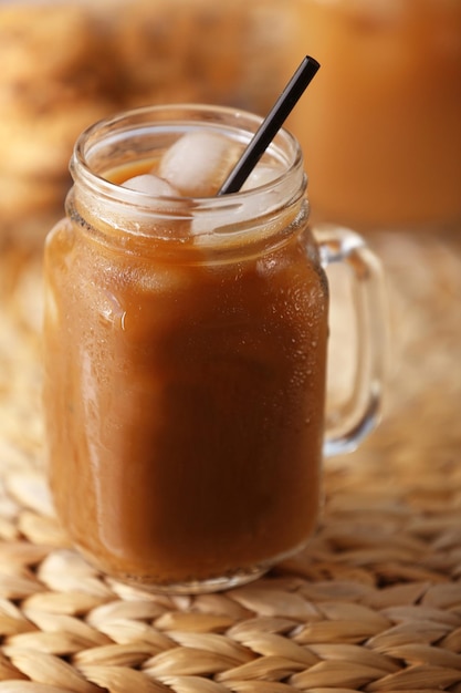 Iced coffee in glass jar on wicker table