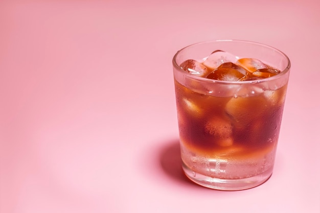 Iced coffee in a glass on pink background Cold refreshment summer drink