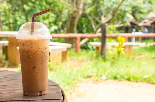 Caffè freddo in vetro sul tavolo erba e albero di sfondo.