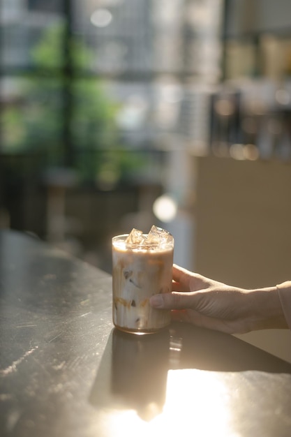 Latte di caffè ghiacciato su un tavolo con la panna che viene versata al suo interno, mostrandone la consistenza.