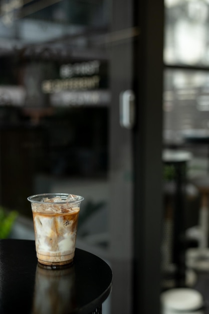 Iced coffee in plastic cup on black table with sunlight background