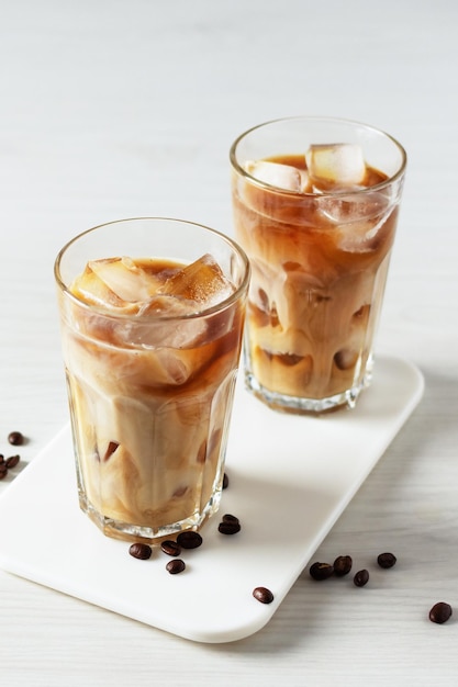 Iced coffee in a tall glass on white wooden table