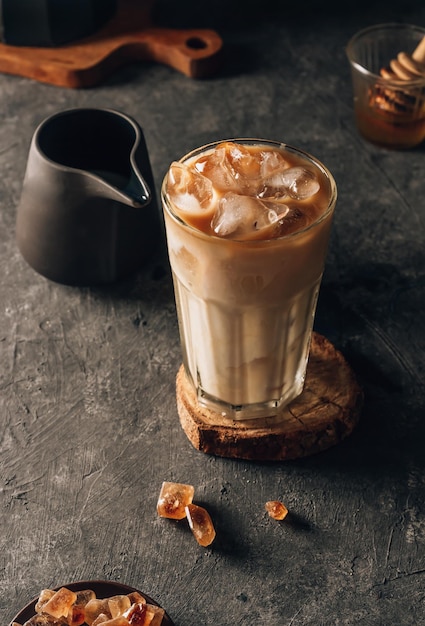 Iced coffee in a tall glass with cream poured over Dark mood background Selective focus
