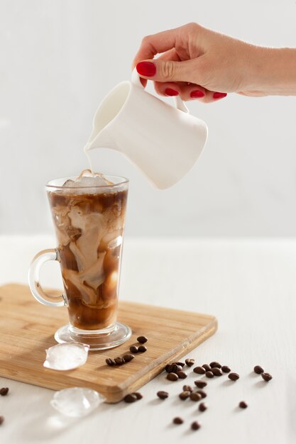 Iced coffee in a tall glass with cream poured over.