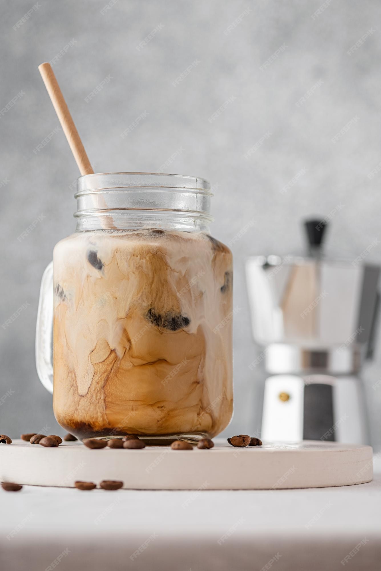 Premium Photo  Iced coffee with milk or cream in a glass jar with a straw  on gray background cold refreshment summer drink