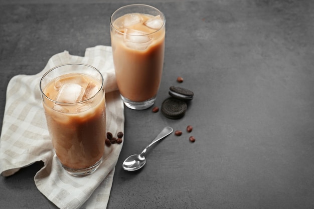 Iced coffee with milk in glasses on grey background