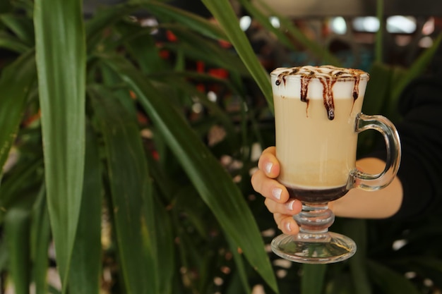 Iced coffee with milk. Iced coffee latte . Woman holding glass cup of iced coffee.