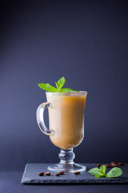 Фото Ледный кофе с молоком на темном фоне латте и свежая мята на сланцевой доске летний напиток в стакане