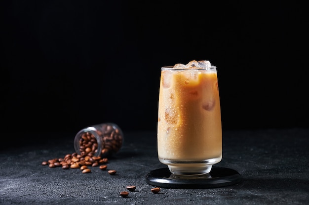 Iced Coffee with Milk in Tall Glass on Dark Background. Concept Refreshing Summer Drink.