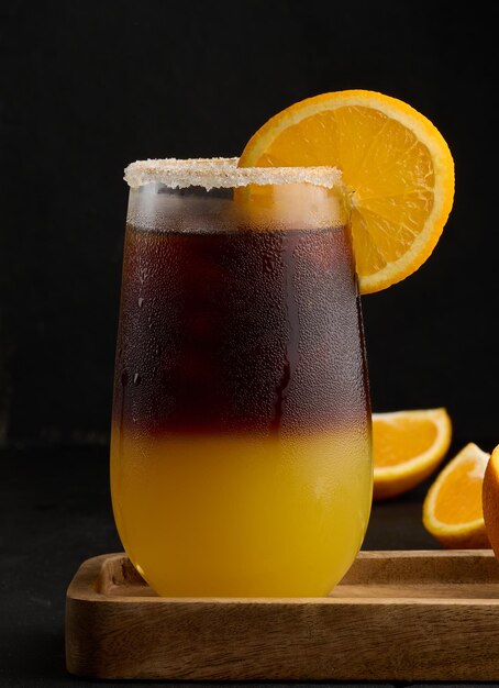 Iced coffee with orange juice in a transparent glass refreshing bumble coffee on the table black background