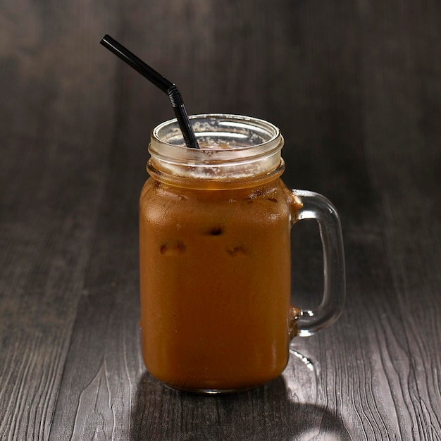 Iced Coffee with straw served in mug isolated on table side view healthy morning drink