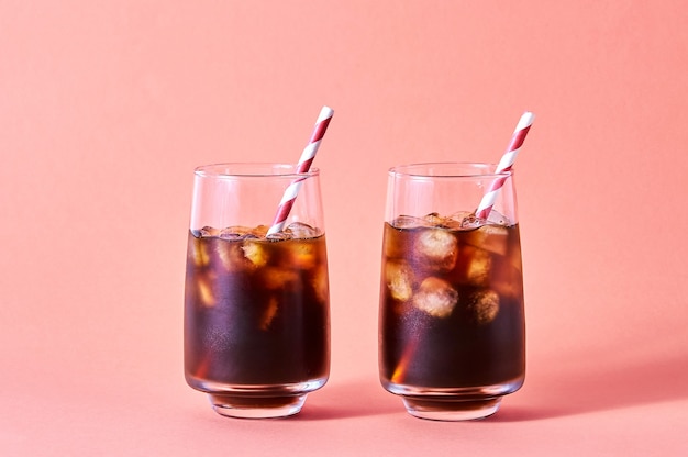 Iced cola or cold coffee in tall glasses on pink background