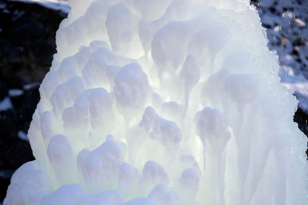 Ледяной фонтан в парке в зимний солнечный день Фонтан с замерзшей водой