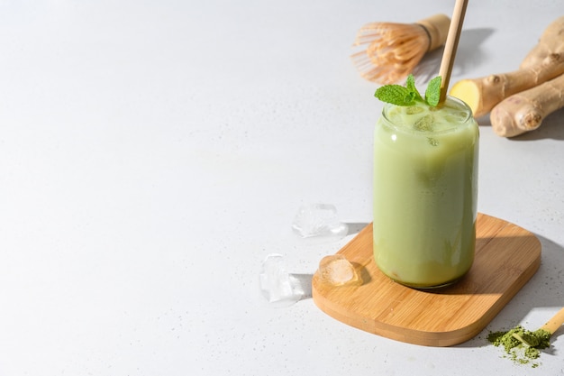 Tè verde ghiacciato del latte di matcha sulla tavola bianca. avvicinamento.