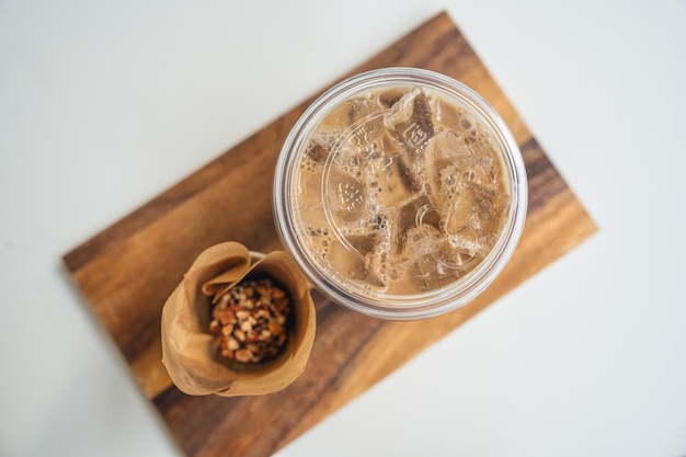 Iced Latte coffee in plastic glass and dessert chocolate ball on wooden tray