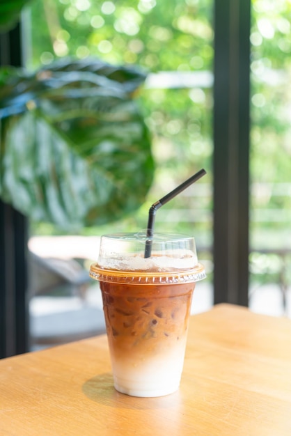 iced latte coffee in takeaway glass on table in coffee shop cafe restaurant