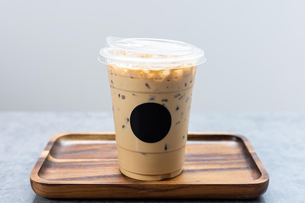 Iced latte coffee on wooden tray with black logo sticker.