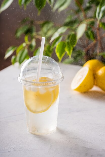 Iced lemonade with soda in plastic glass on the table