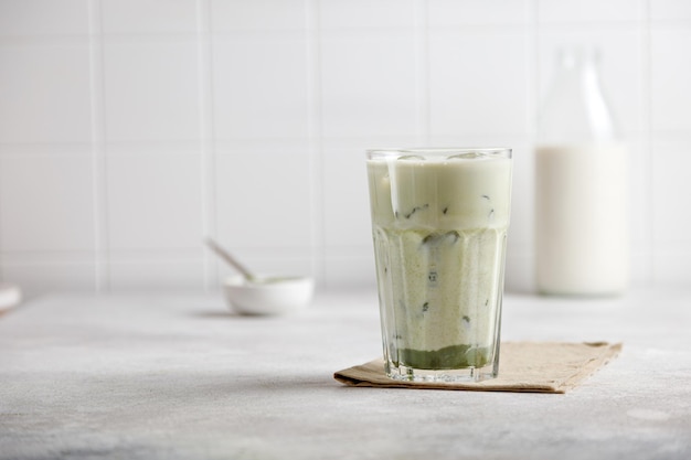 Iced matcha green tea with milk and ice on a gray table