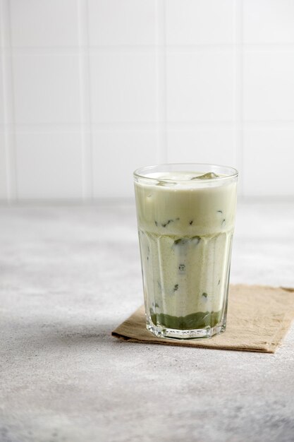 Iced matcha green tea with milk and ice on a gray table