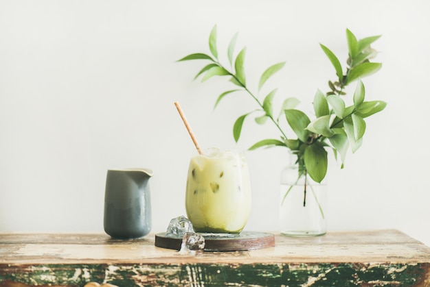 Iced matcha latte with milk pouring from pitcher horizontal composition