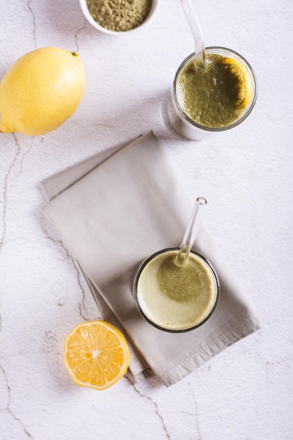 Iced matcha lemonade with lemon in glasses with straws on the table top and vertical view