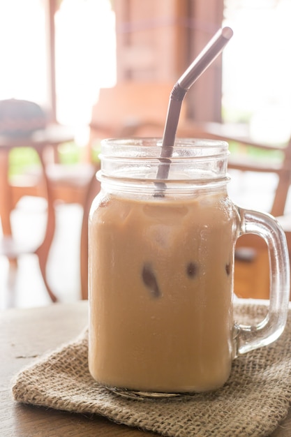 Iced milk coffee glass on wooden table with vintage filter effect