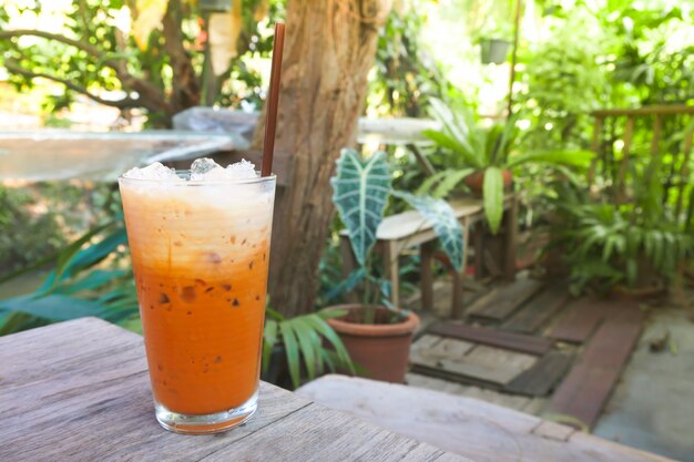 Tè freddo al latte in vetro moderno con vista sul giardino naturale, bevanda tailandese