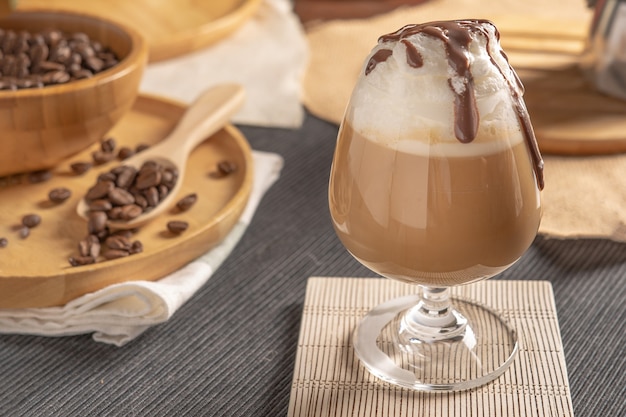 Iced mocha coffee served with whipped cream topping and chocolate syrup in wine glass place on wooden table