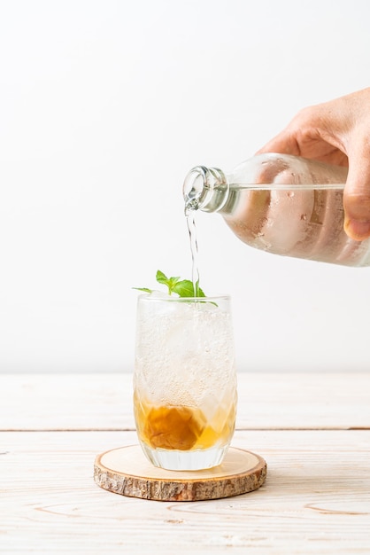 iced plum juice with soda and peppermint on wood table - refreshment drink