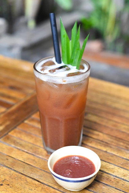 Iced plum tea with jam on wooden planks background