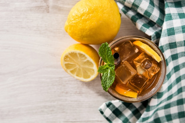 Iced tea drink with lemon in glass and ice