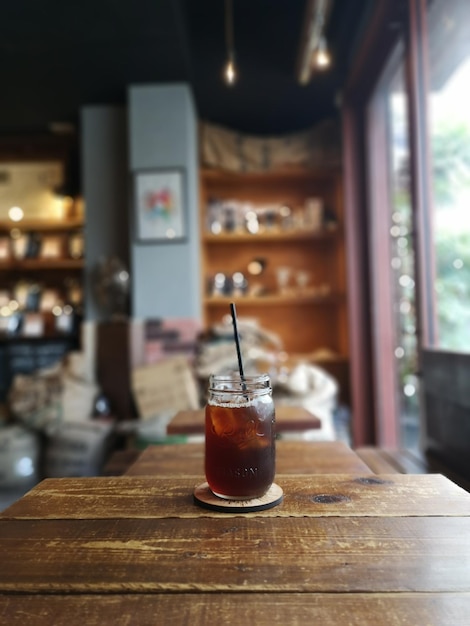 iced tea in a large glass with a straw with a cafe background