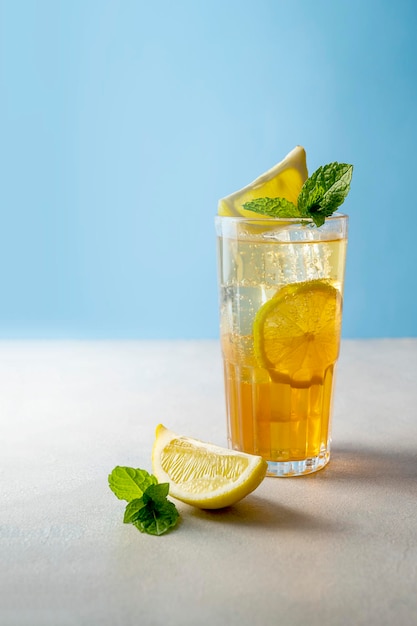 Iced tea with lemon and fresh mint blue background