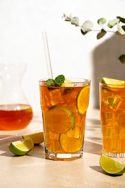 Iced tea with lemon fresh mint leaves and ice in tall glasses with sun light and shadows